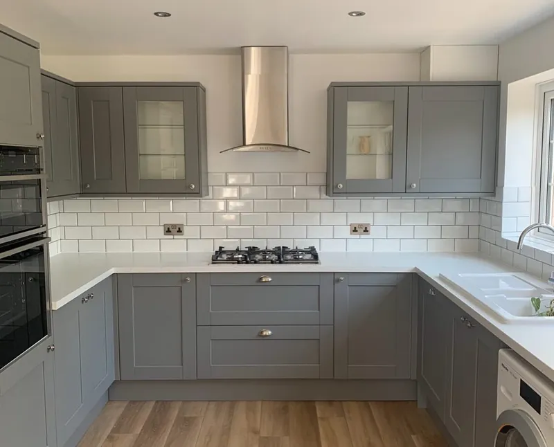 Grey shaker kitchen with white metro tiles, gas hob, chimney extractor and built-in oven